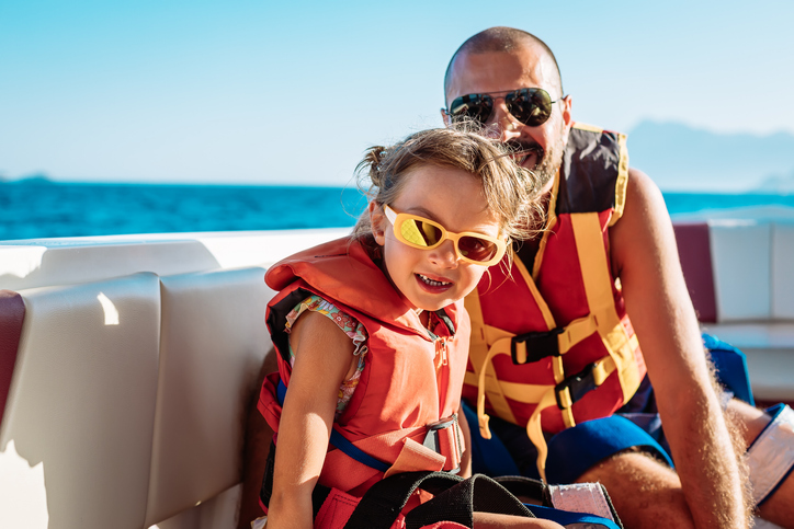 Little girl and her father wearing orange life jackets
